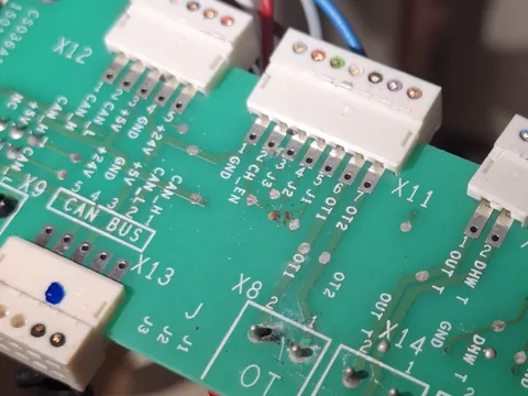 Detalle de una placa electrónica verde con conectores blancos y la serigrafía de sus bornas